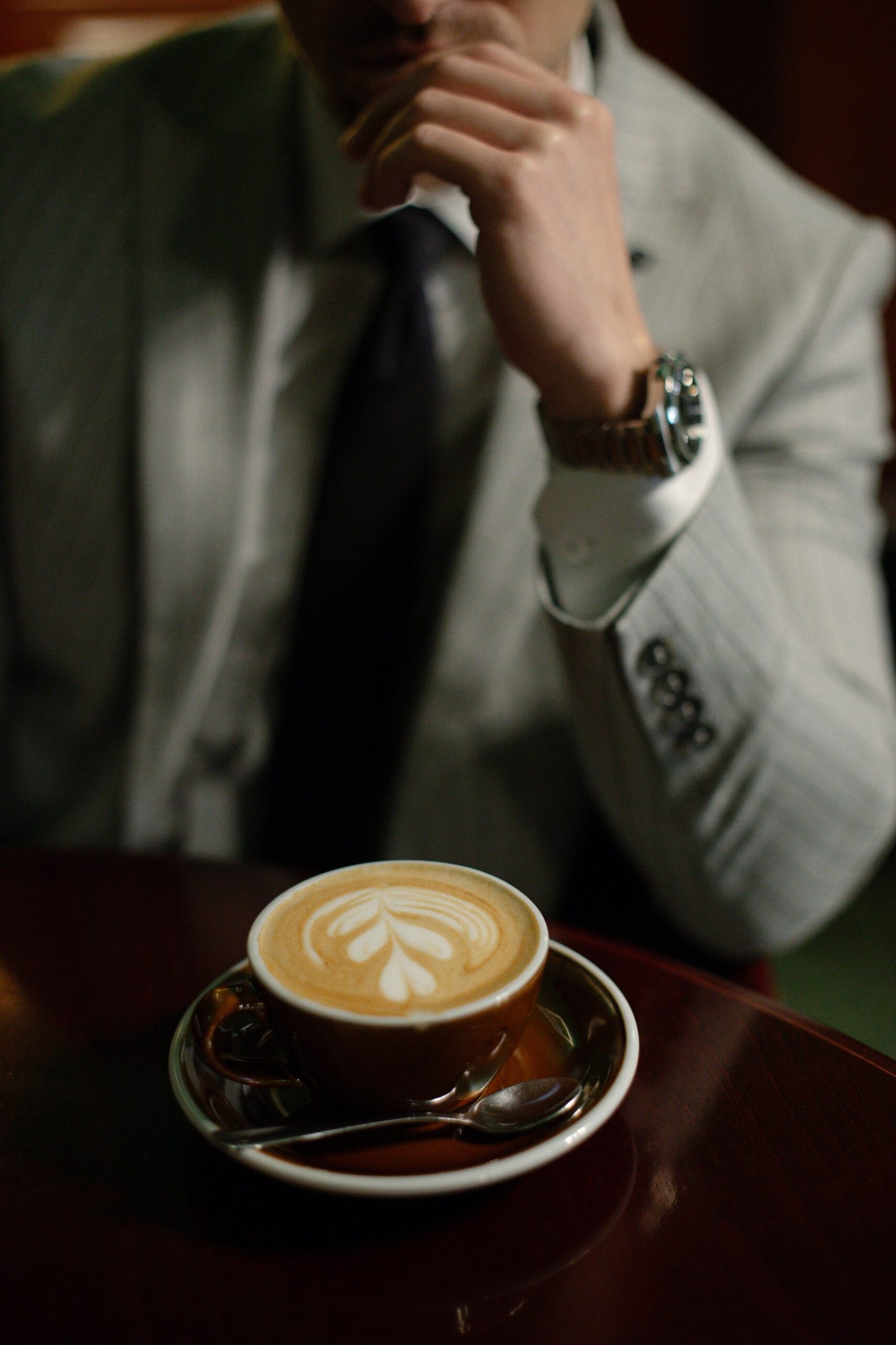 A stylish man in a suit enjoys a latte with art in a Slovakian cafe.